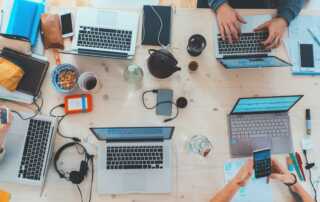 people sitting down near table with assorted laptop computers